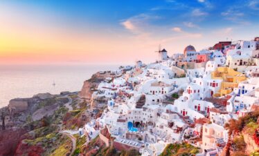 Iconic whitewashed houses and windmills of Oia in Santorini at sunset, overlooking the Aegean Sea.