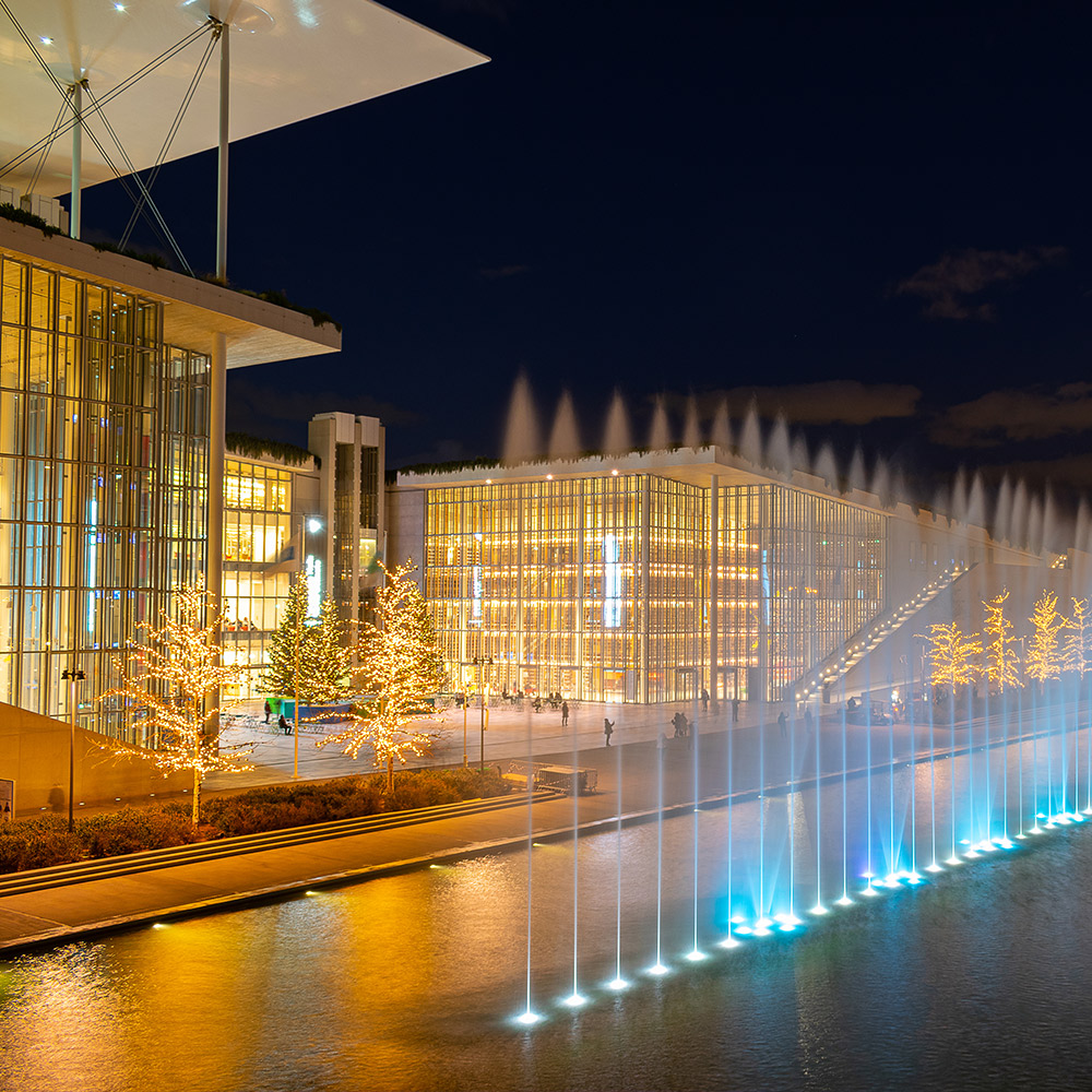 Illuminated modern conference venue with water fountains at night in Athens, ideal for large-scale events and conventions.