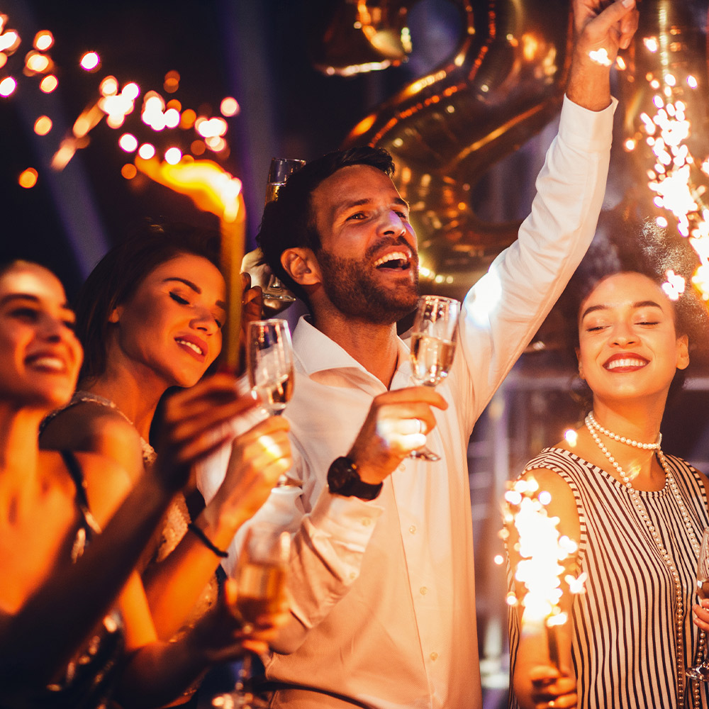 Group of people celebrating with sparklers and champagne at a corporate event, showcasing vibrant atmosphere and flawless coordination.