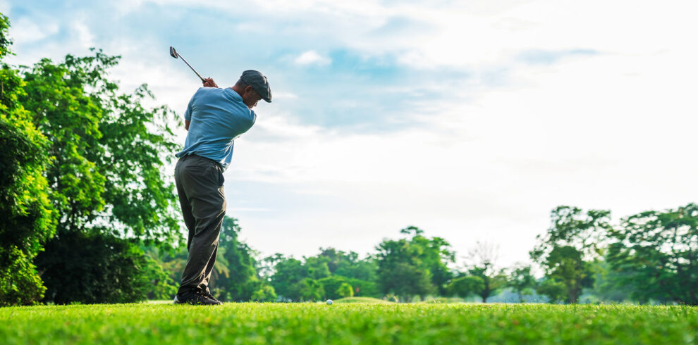 Golfer swinging a club on a lush green course under a bright sky, capturing the essence of golfing in nature.