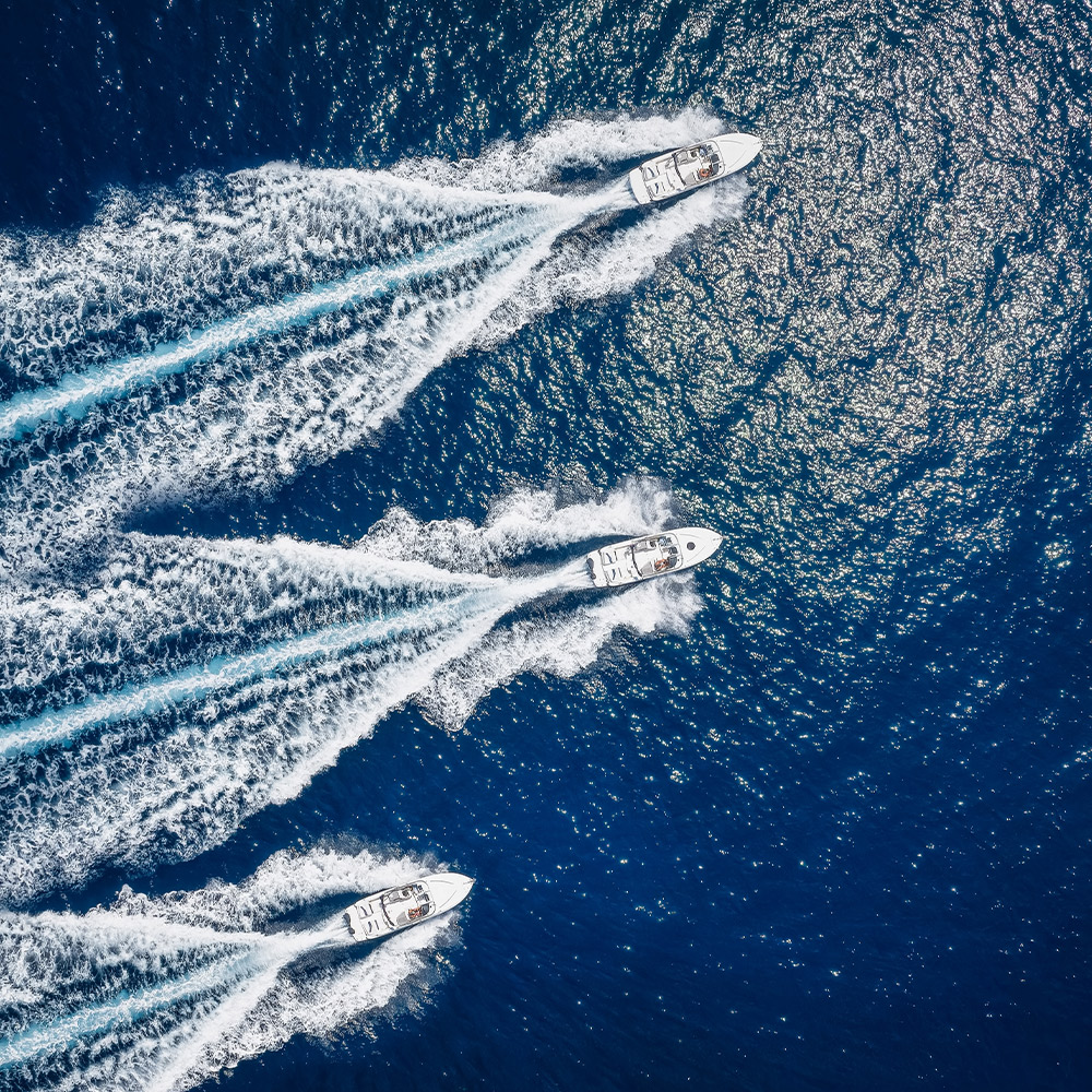 Aerial view of three speedboats cutting through deep blue waters, symbolizing dynamic team incentives and luxury experiences.