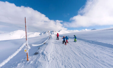 Skiers on a snowy mountain slope under a bright blue sky, enjoying winter sports in a Greek ski resort.