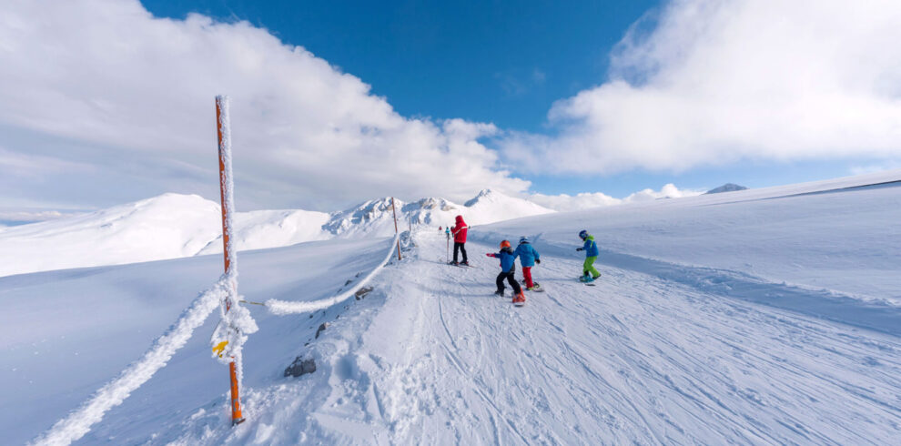 Skiers on a snowy mountain slope under a bright blue sky, enjoying winter sports in a Greek ski resort.