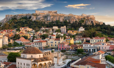 Panoramic view of Athens with the Acropolis rising above the historic Plaka district and ancient ruins below.