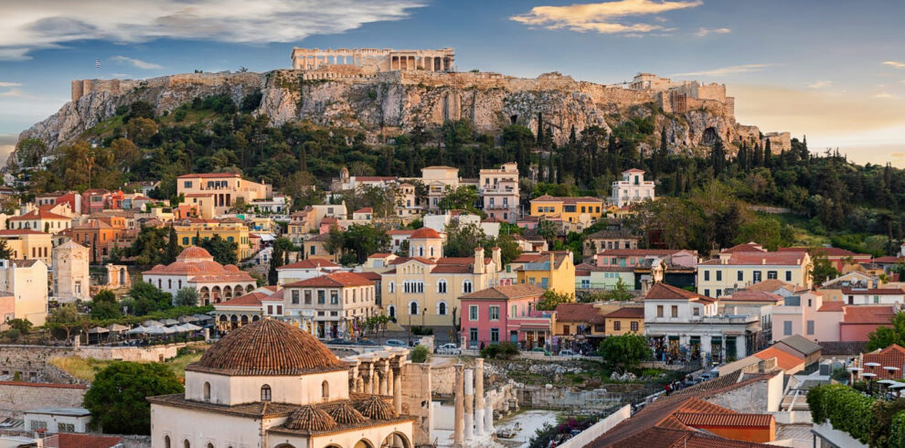 Panoramic view of Athens with the Acropolis rising above the historic Plaka district and ancient ruins below.