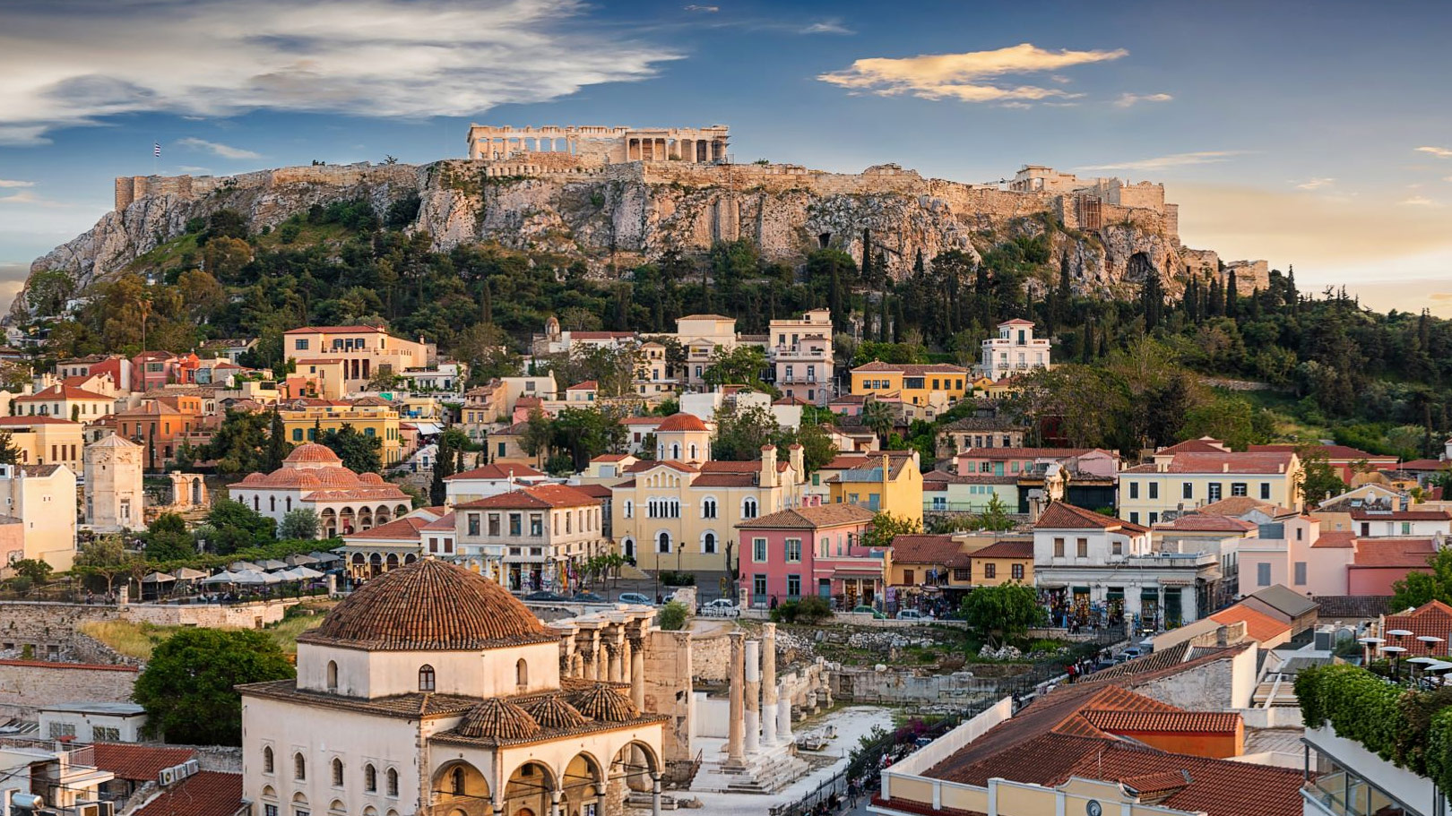 Panoramic view of Athens with the Acropolis rising above the historic Plaka district and ancient ruins below.