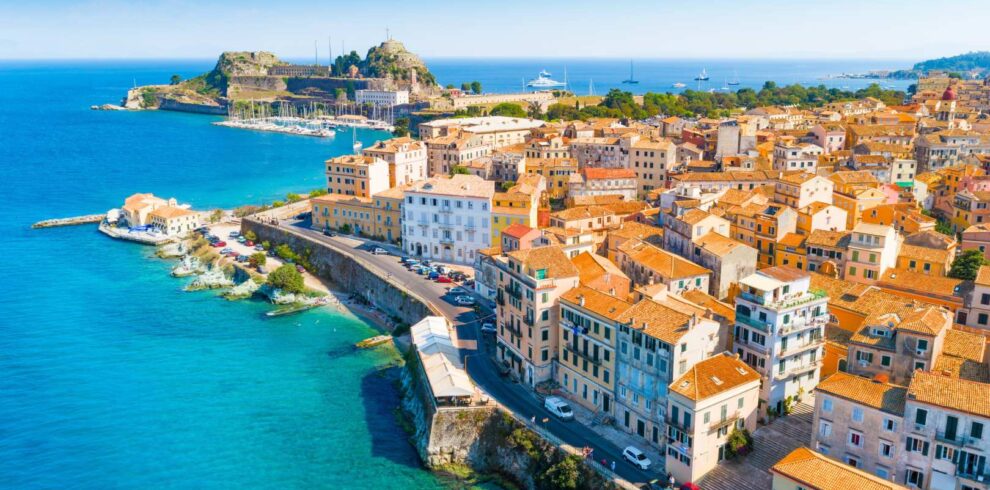 Aerial view of Corfu’s old town with colorful Venetian buildings, coastal walls, and the Ionian Sea in the background.