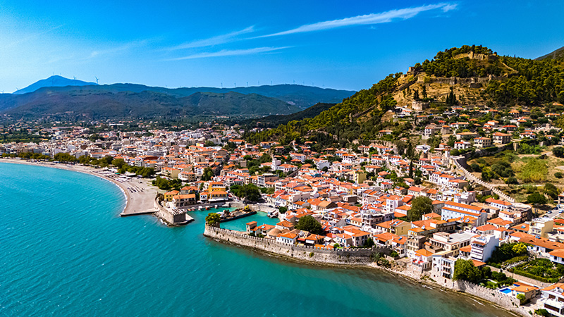 Aerial view of the coastal town of Nafpaktos, Greece, with its Venetian harbor, beach, and hillside fortress.