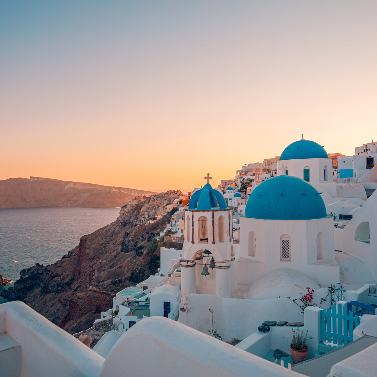 Blue domed churches above the Santorini caldera at sunset